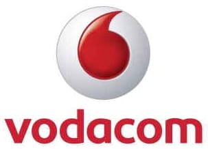 Vodacom logo: A red and white circular emblem resembling a quotation mark or speech bubble, above the word "vodacom" in bold red lowercase letters on a white background.